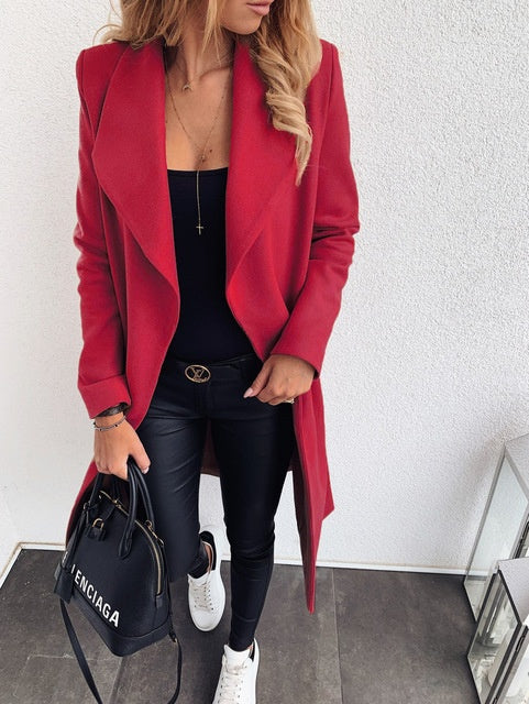 Person wearing a red coat, black top, and pants, holding a black handbag with 'Celine' branding.